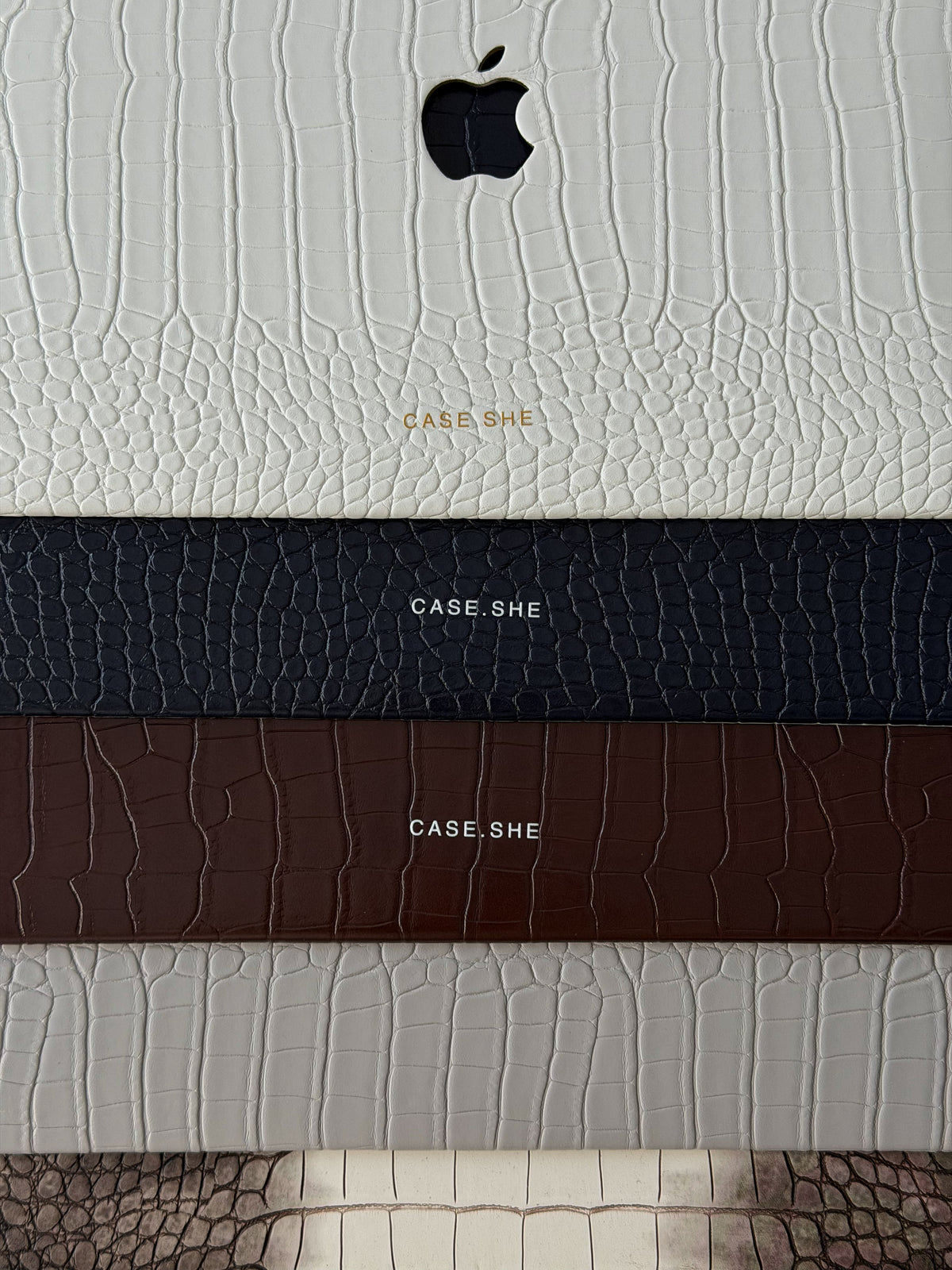Стопка чохлів CASE.SHE для MacBook із фактурою під шкіру крокодила: молочний, темно-синій, коричневий, сірий і градієнтний
