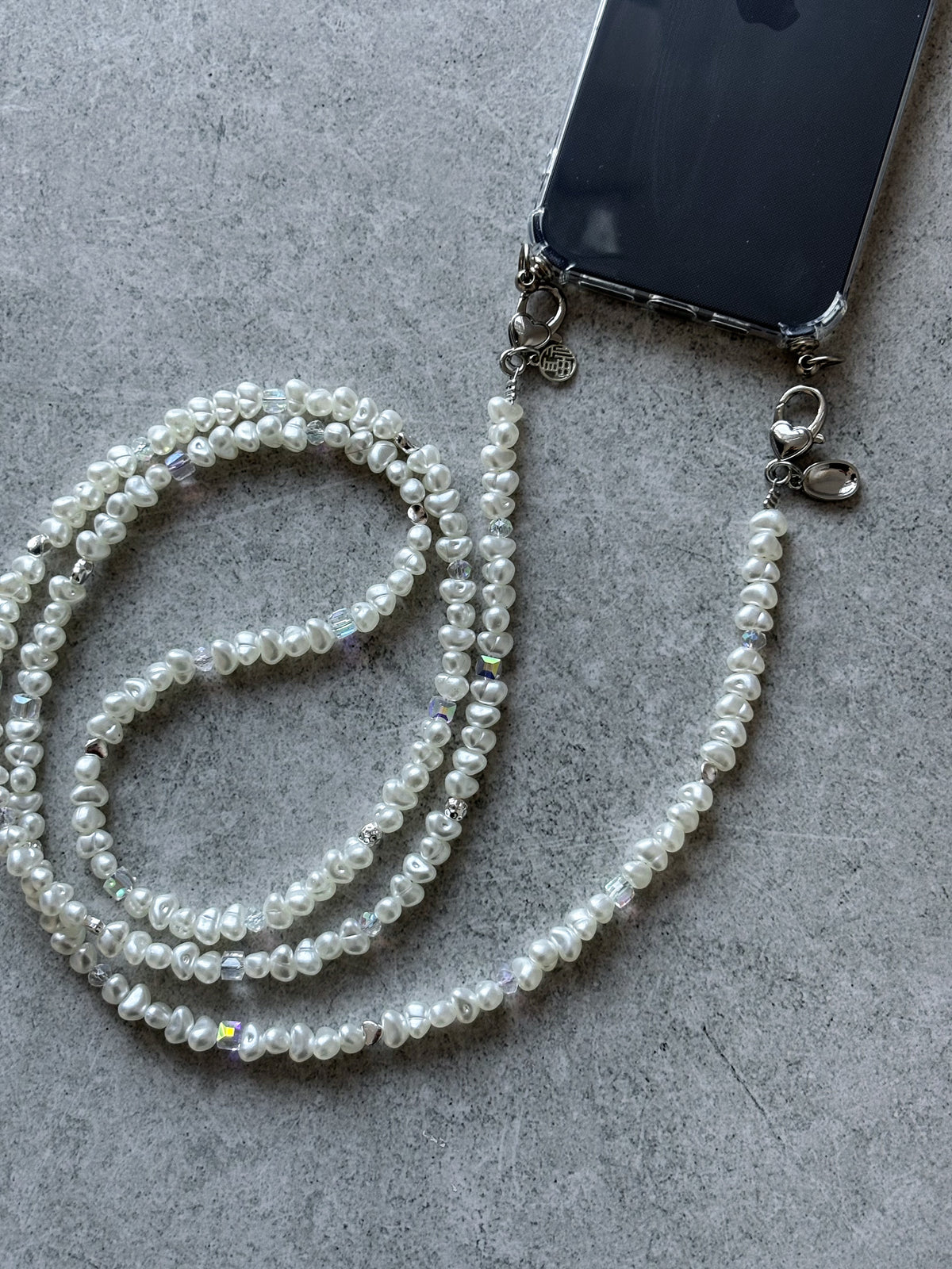 Ланцюжок Crystal Pearl на телефоні в прозорому чохлі на сірому бетоні