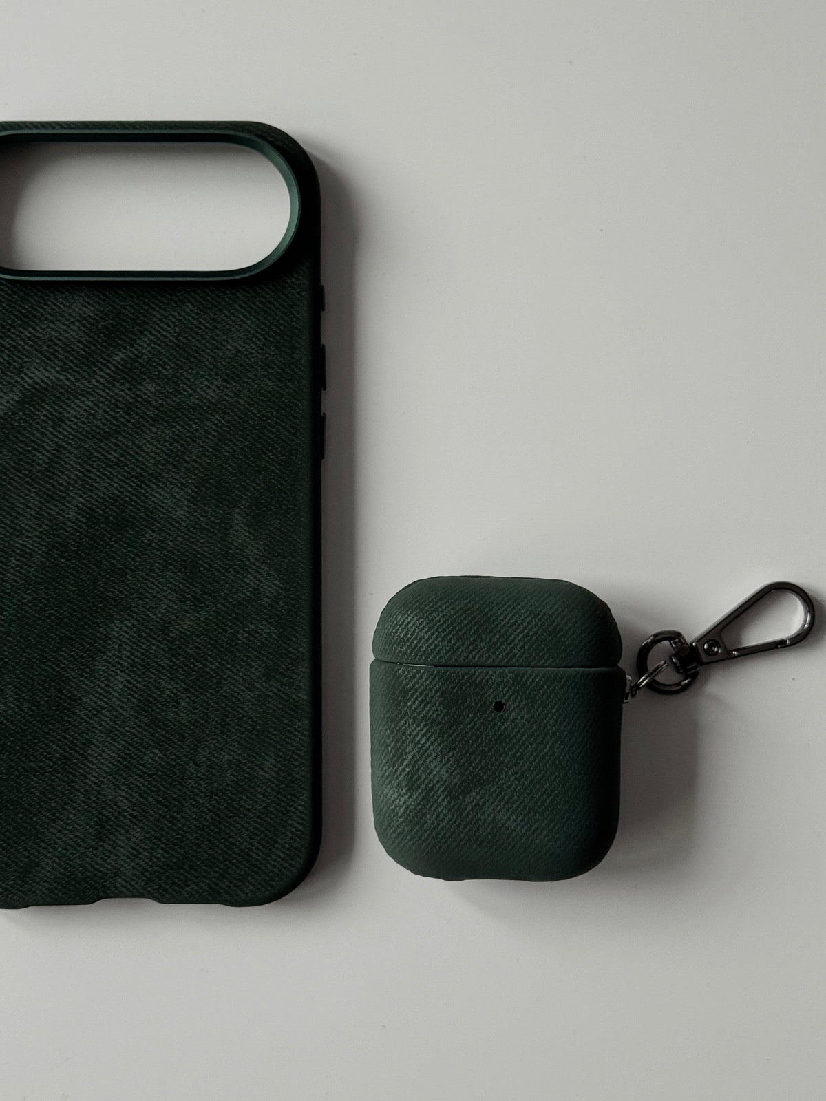 Темно-зелений чохол «Замшева м’якість» на вужчому кейсі AirPods поруч із чохлом для iPhone