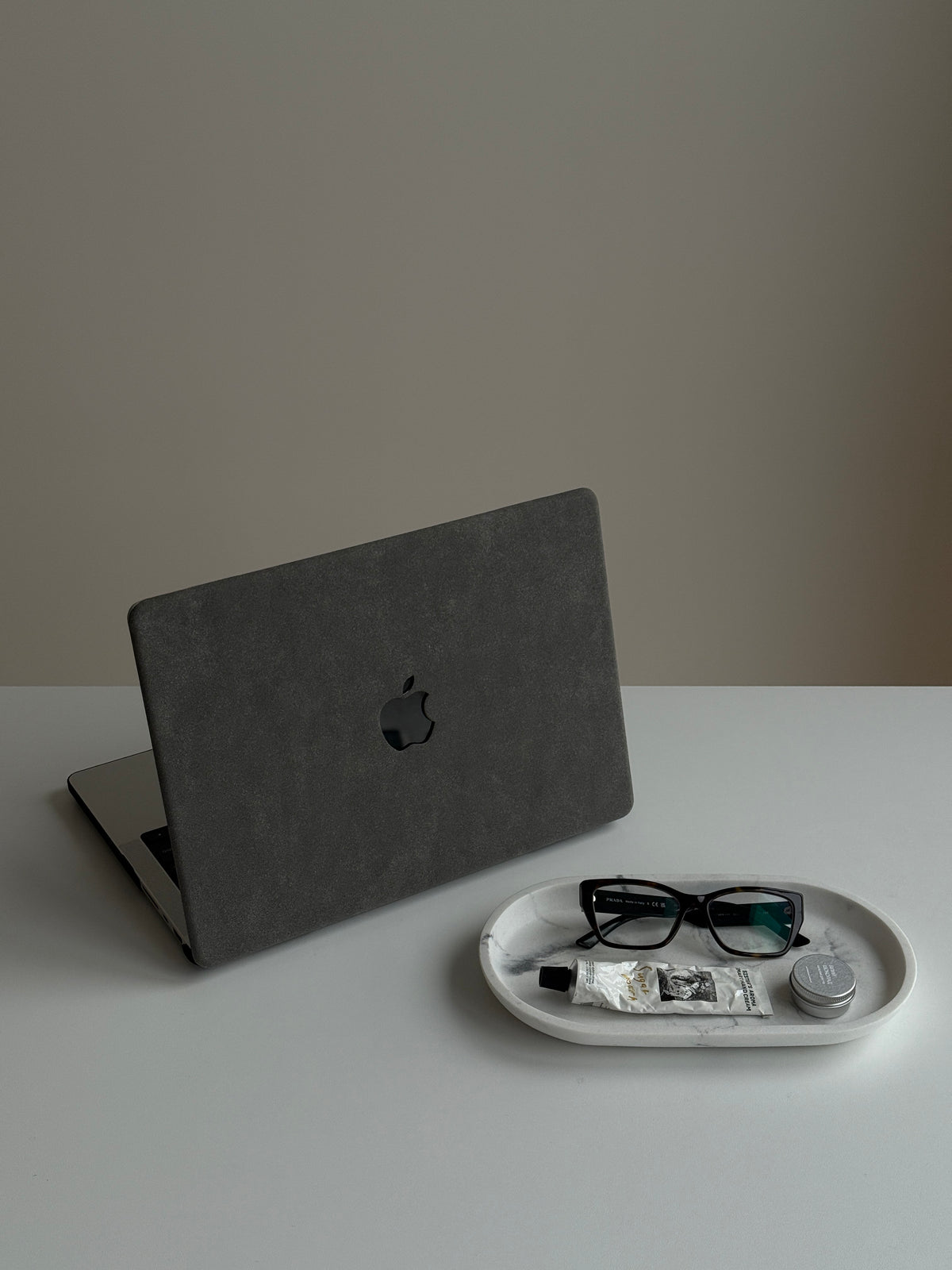 Сірий чохол «Замшева м’якість» на напіввідкритому MacBook поруч з окулярами на таці