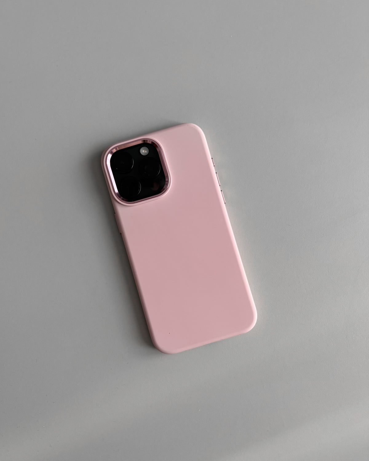 Рожевий чохол на iPhone з квадратним вирізом під камеру — вигляд ззаду на сірому тлі