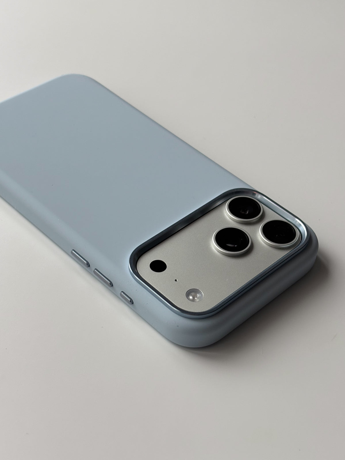 Світло-блакитний чохол для iPhone лежить на білій поверхні — вигляд під кутом