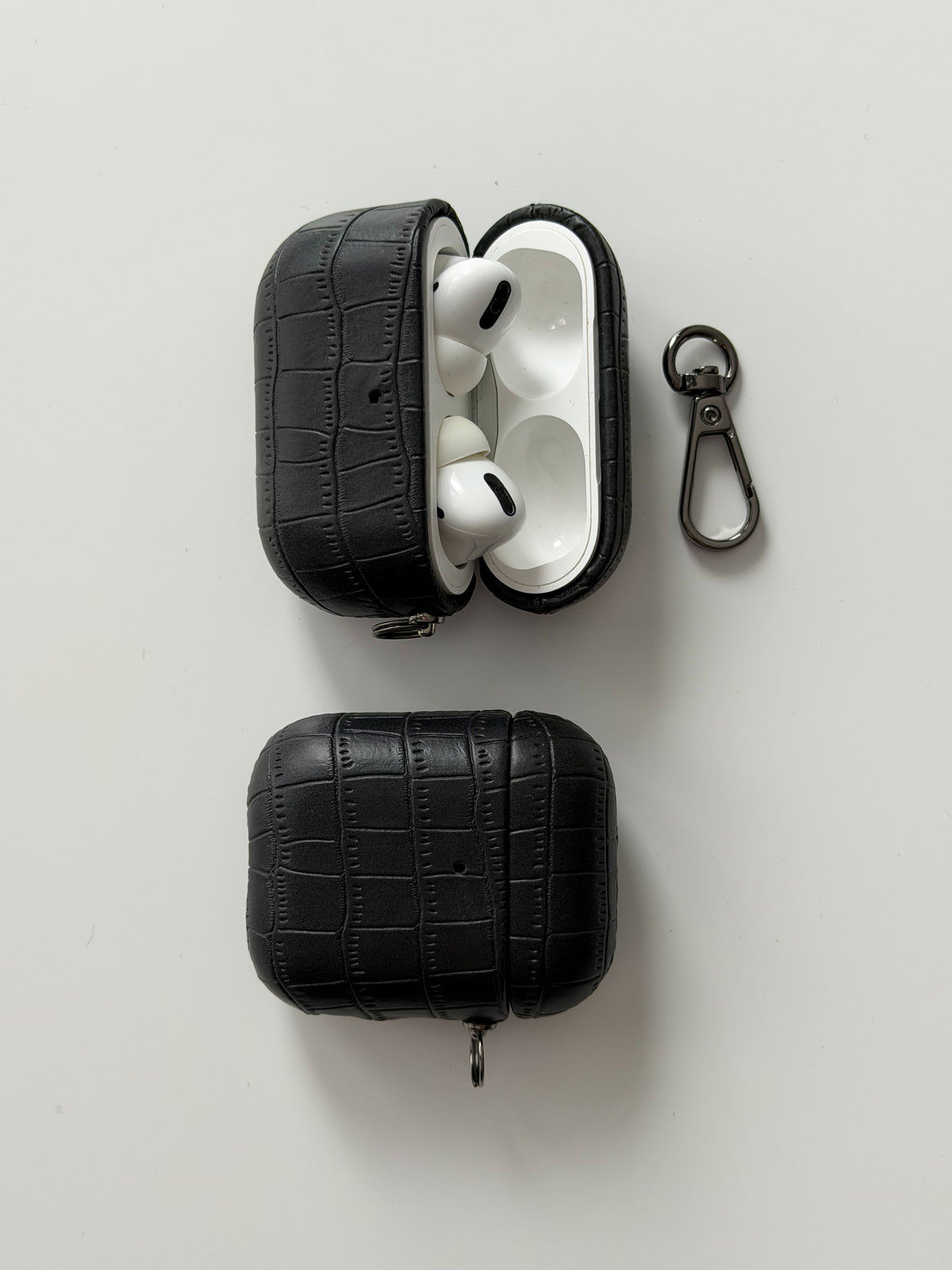 Два чорні чохли Gator Skin для AirPods — відкритий і закритий, поруч карабін