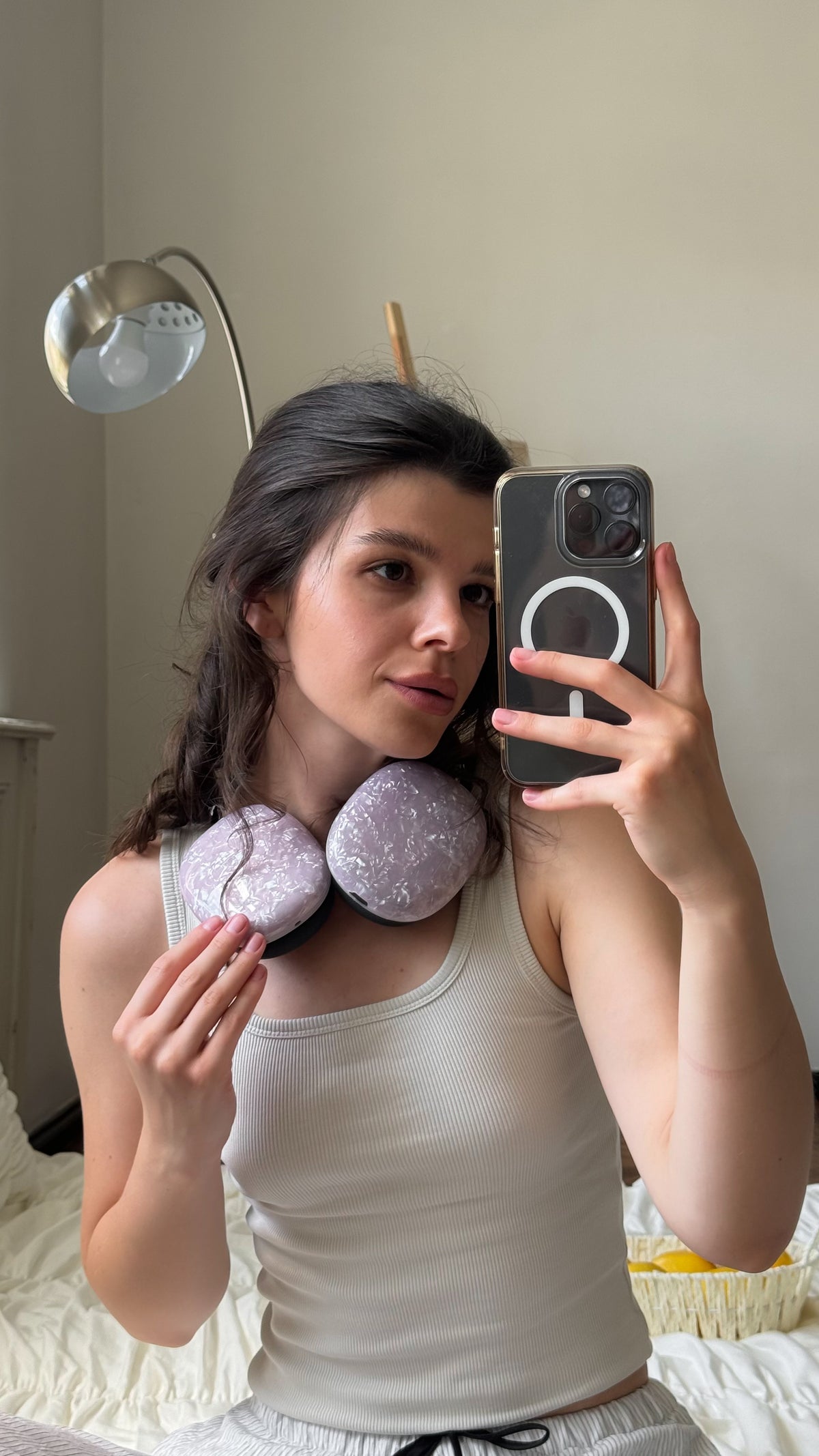 Жінка з AirPods Max у накладках «Кришталеве сяйво» на шиї робить селфі в дзеркалі