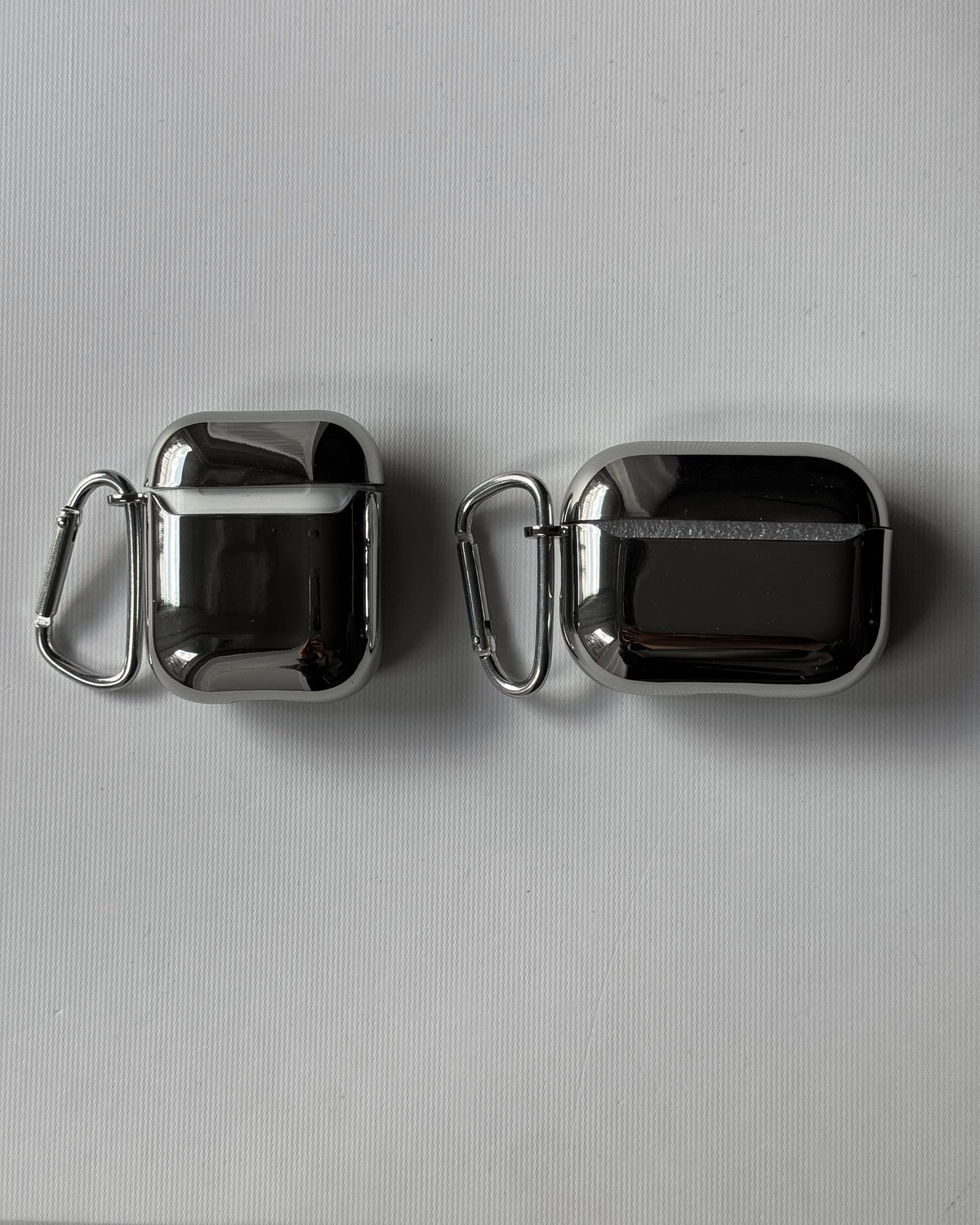 Дзеркальні сріблясті чохли для AirPods — два кейси з карабінами поруч
