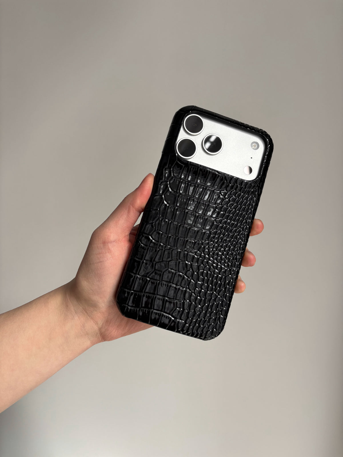Чорний глянцевий чохол Gator Skin на iPhone у руці під нахилом