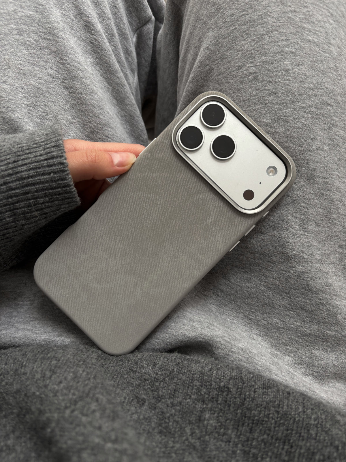 Сірий чохол на iPhone притиснутий до сірого светра