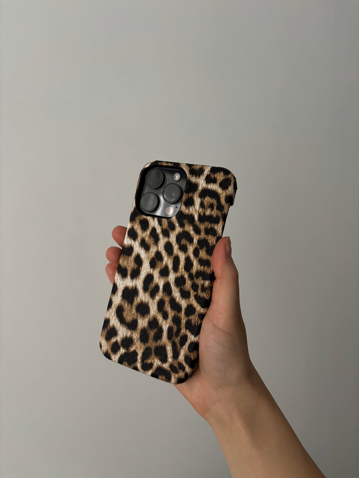 Пісочний леопардовий чохол на iPhone у витягнутій руці