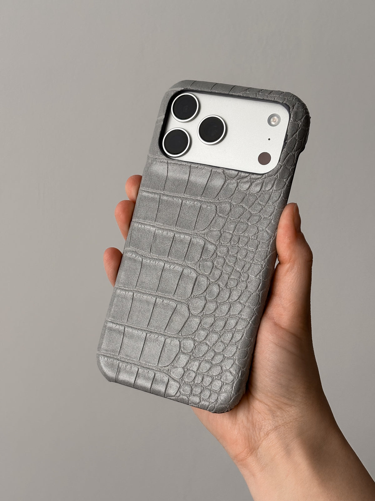 Сірий чохол Gator Skin на iPhone у руці на світлому тлі