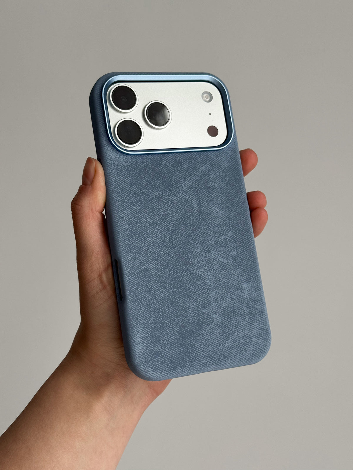 Блакитний чохол «Замшева м’якість» на iPhone зі світлим блоком камер у руці