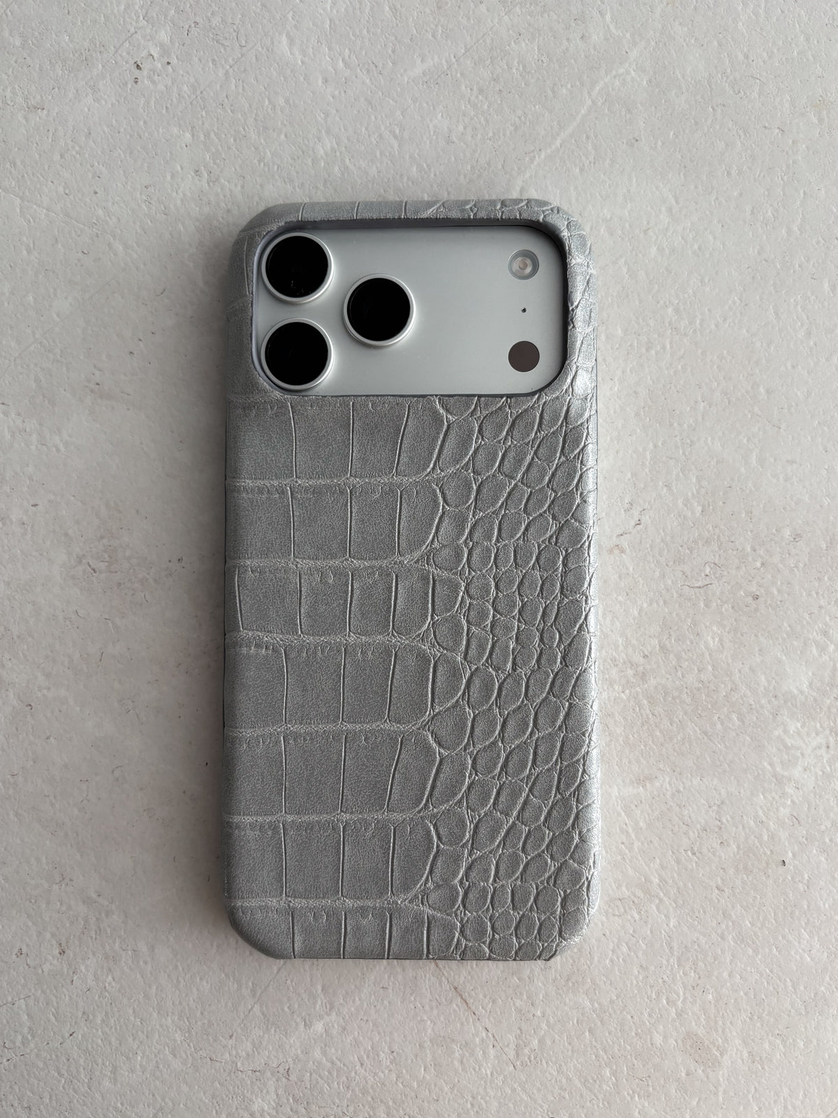 Сірий чохол Gator Skin для iPhone на світлій кам’яній поверхні — вигляд ззаду