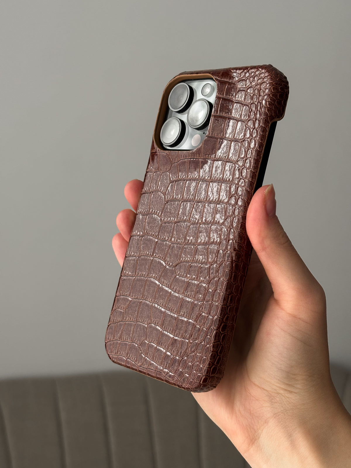 Коньячно-коричневий чохол Gator Skin на iPhone у руці, ракурс під кутом