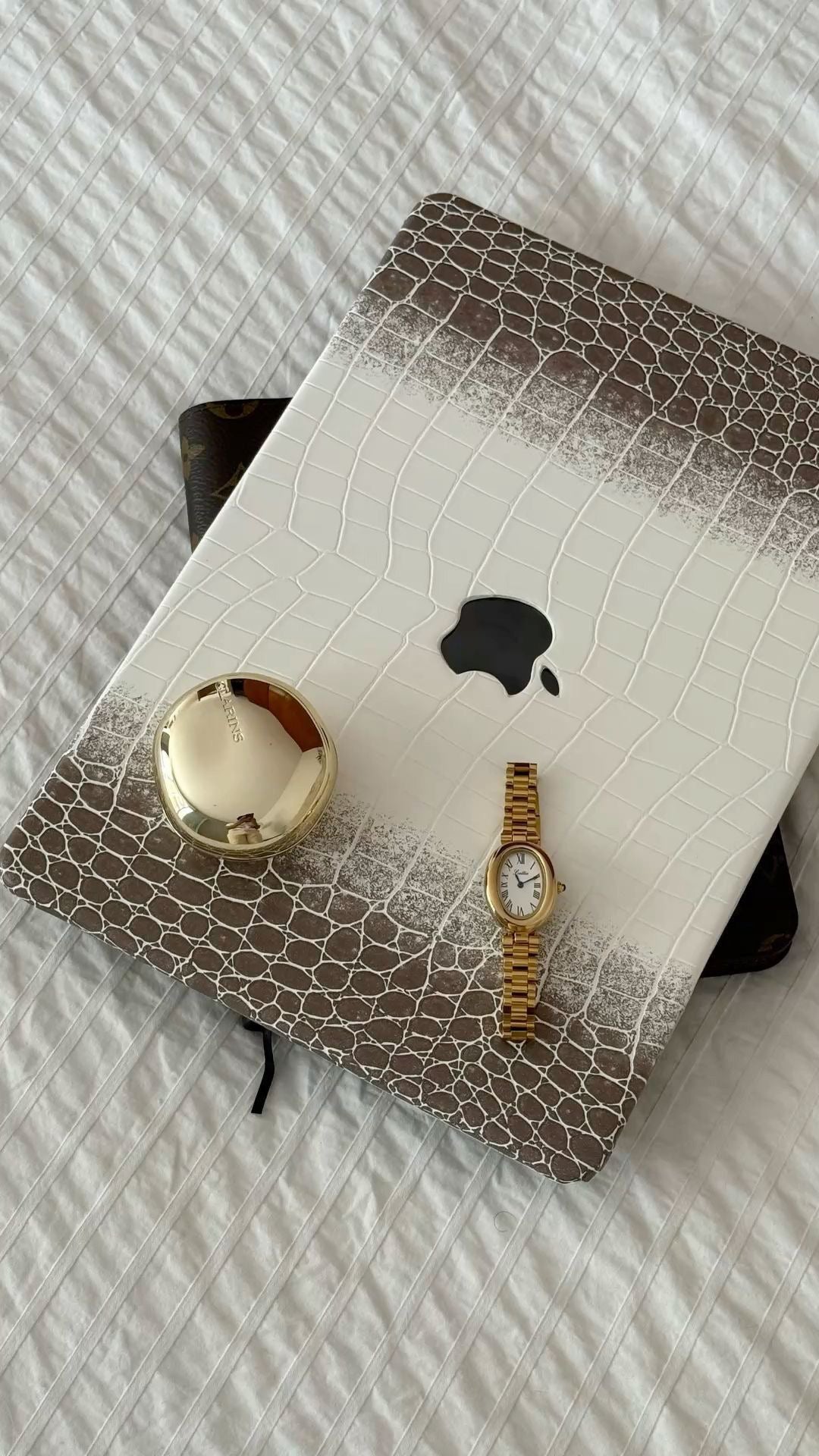 Біло-коричневий чохол Gator Skin для MacBook на білому покривалі з дзеркальцем і годинником