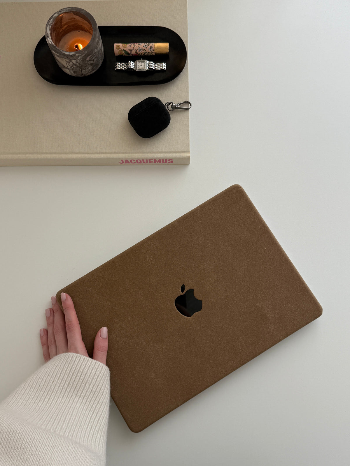 Коричневий чохол «Замшева м’якість» для MacBook поруч зі свічкою, книгою та навушниками в чорному чохлі