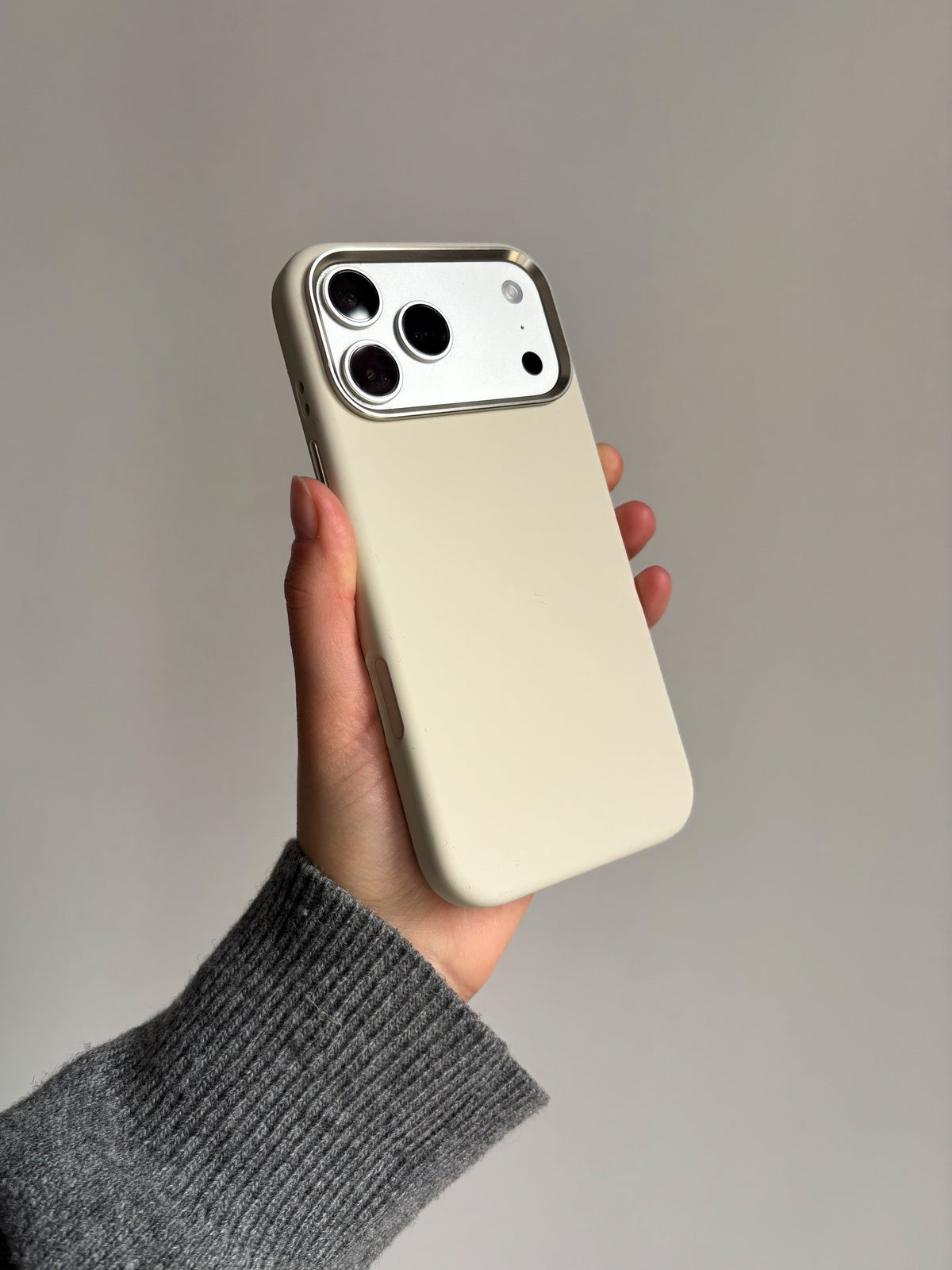 Молочний чохол «Металеві деталі» на iPhone у руці на сірому тлі