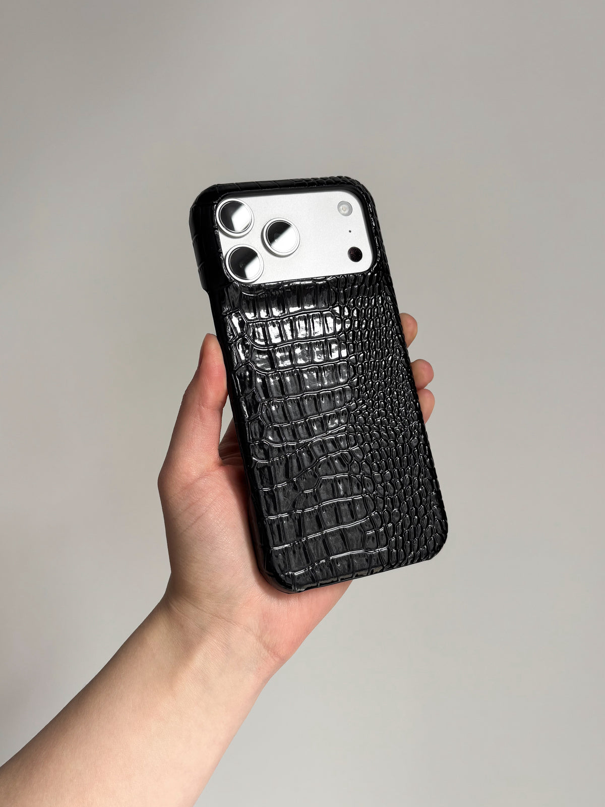 Чорний глянцевий чохол Gator Skin на iPhone у руці, вертикально