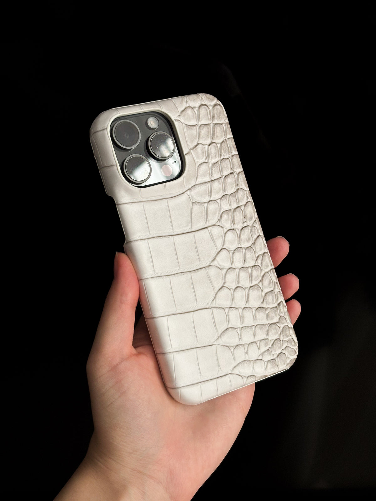 Біло-сірий чохол Gator Skin на iPhone у руці на чорному тлі