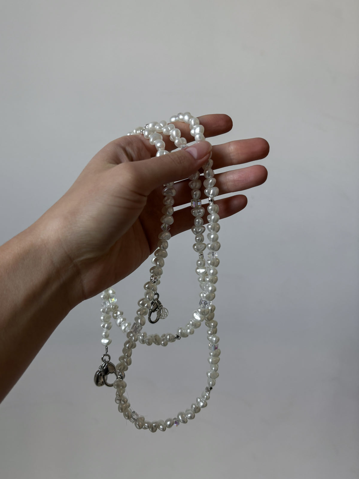 Довгий ланцюжок Crystal Pearl звисає з долоні