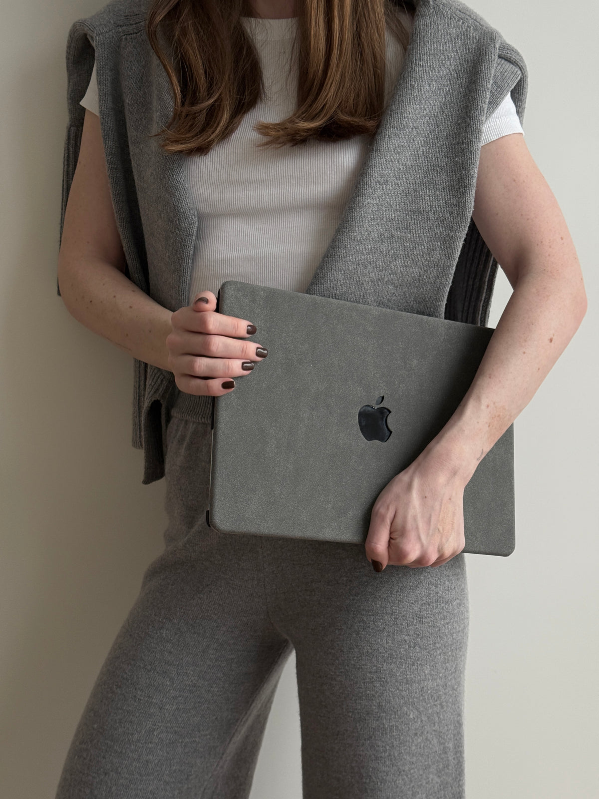 Жінка в сірому трикотажі тримає MacBook у сірому чохлі «Замшева м’якість»