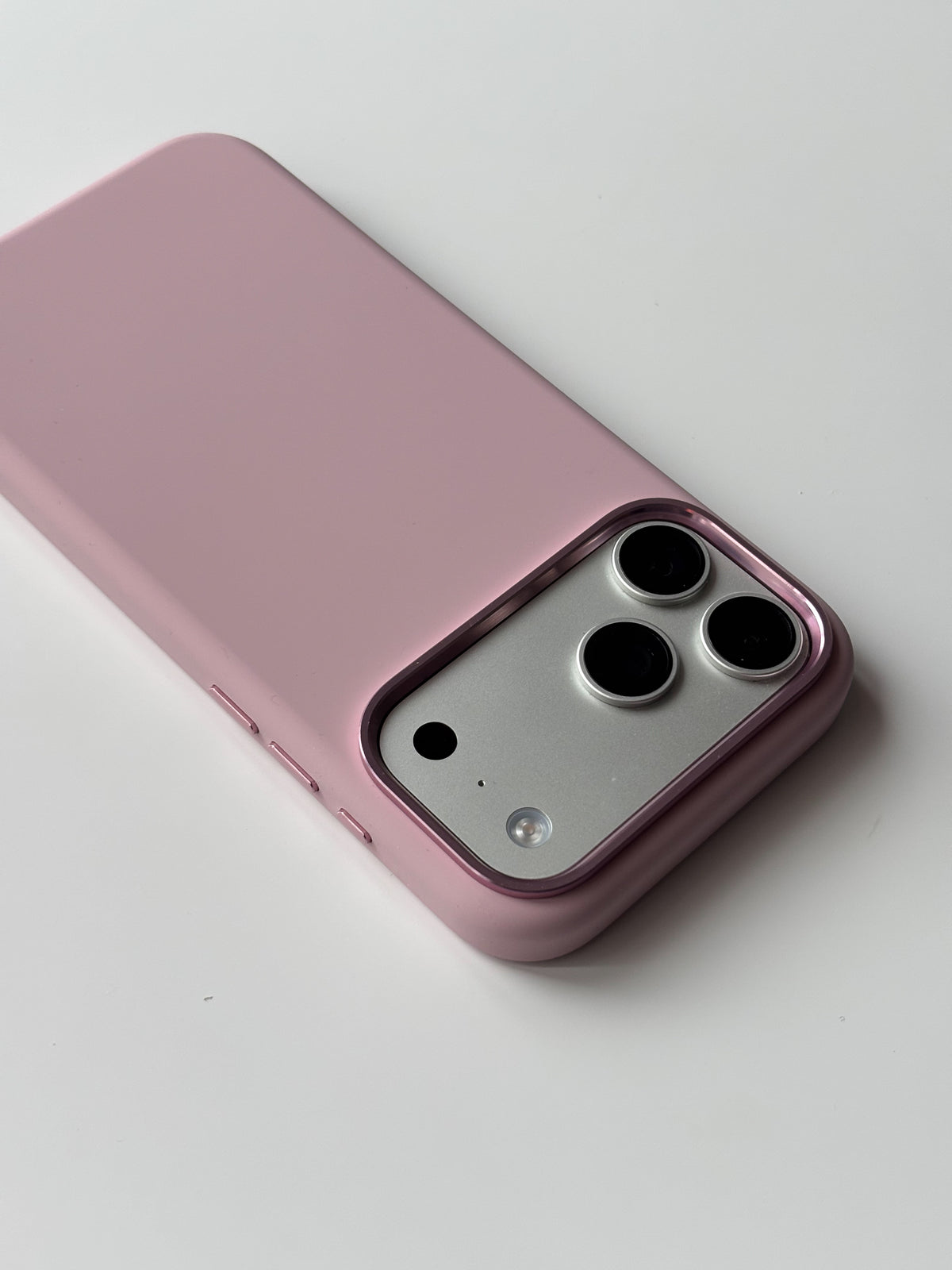 Рожевий чохол для iPhone лежить на білій поверхні — вигляд під кутом