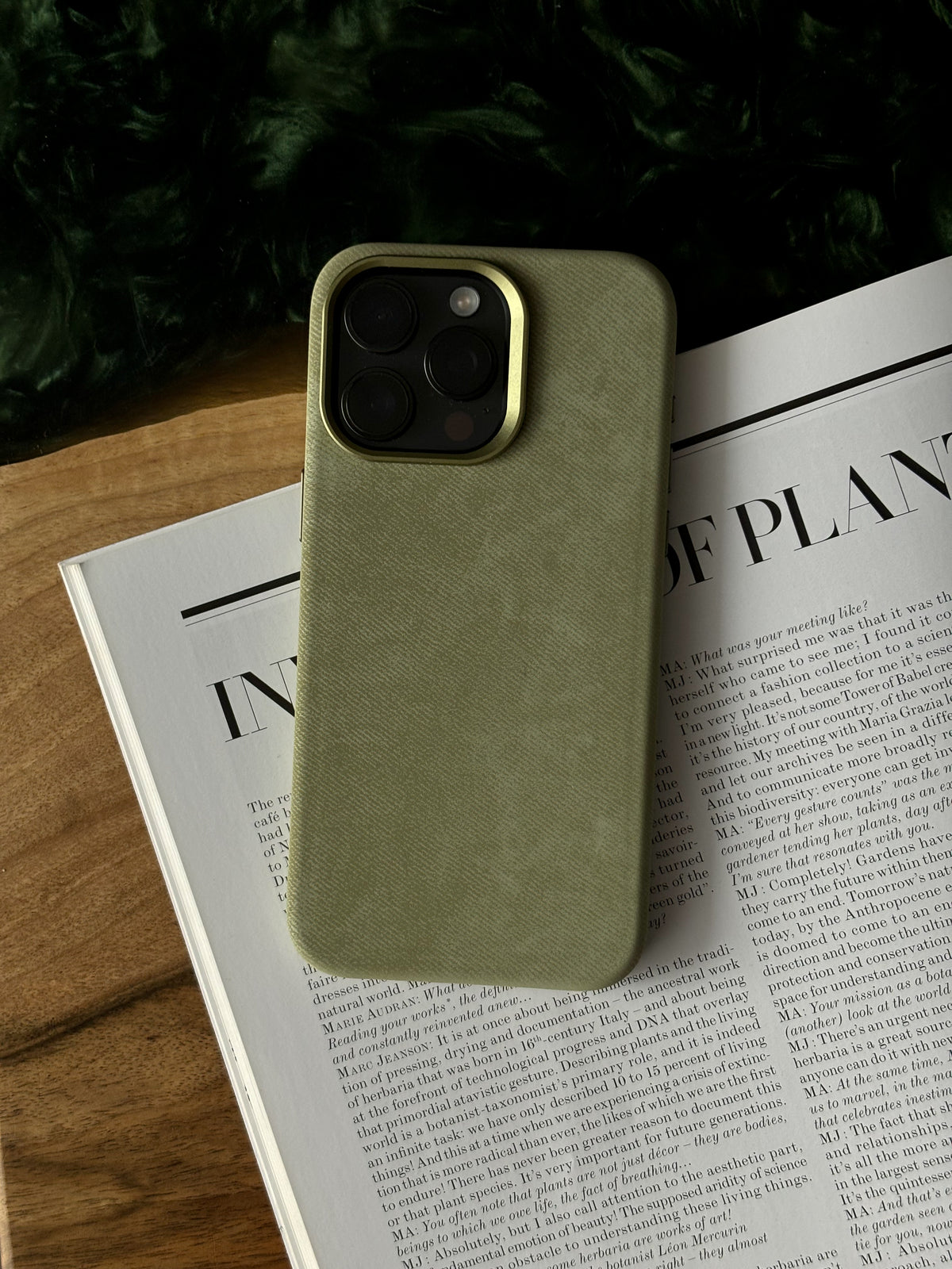 Оливковий чохол для iPhone на розгорнутій газеті на дерев’яному столі
