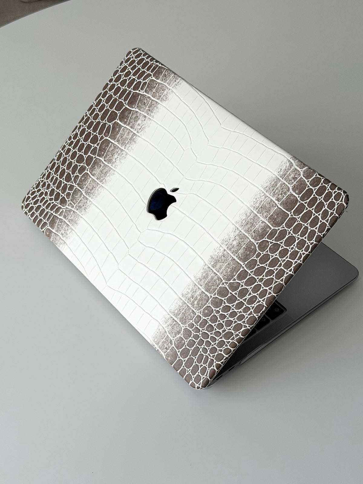 Біло-коричневий чохол Gator Skin на напіввідкритому MacBook — вигляд під кутом