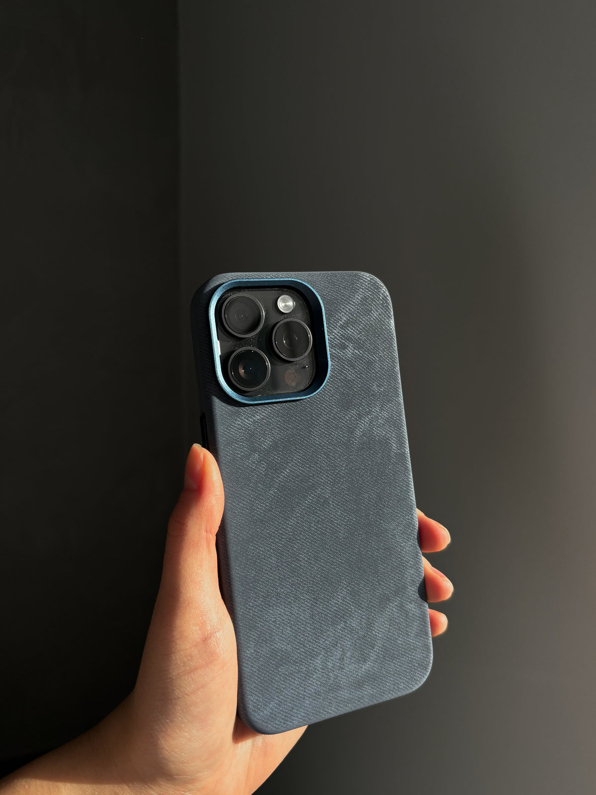 Синій чохол «Замшева м’якість» на iPhone у руці на темному тлі