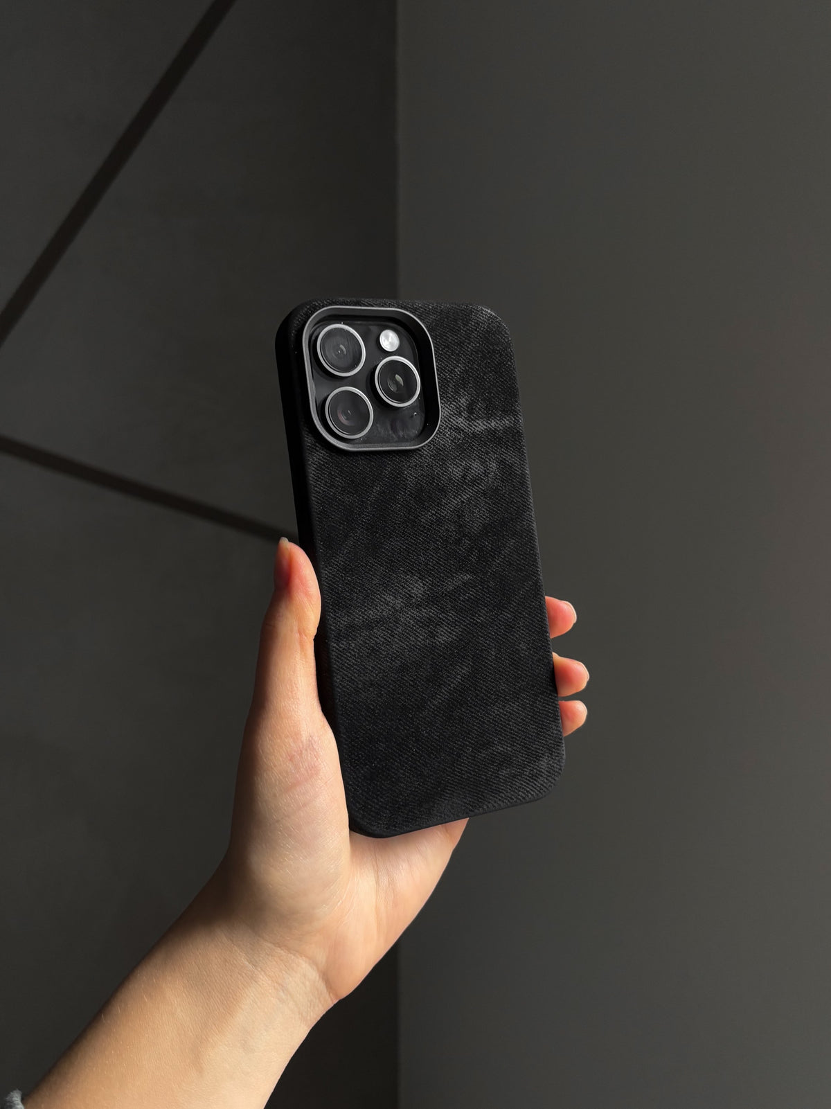 Чорний чохол «Замшева м’якість» на iPhone у руці на темному тлі