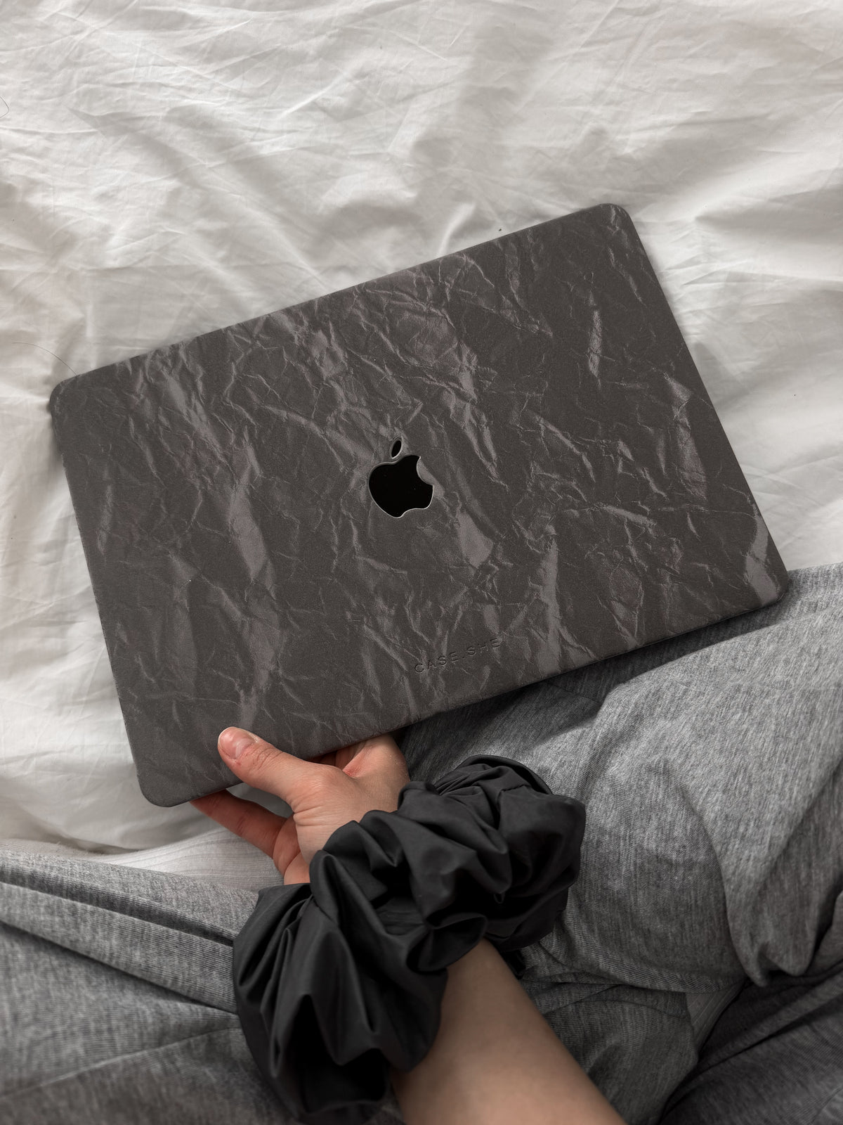 Сірий чохол-накладка «Оксамит» для MacBook із фактурою заломів у руці на білій постелі