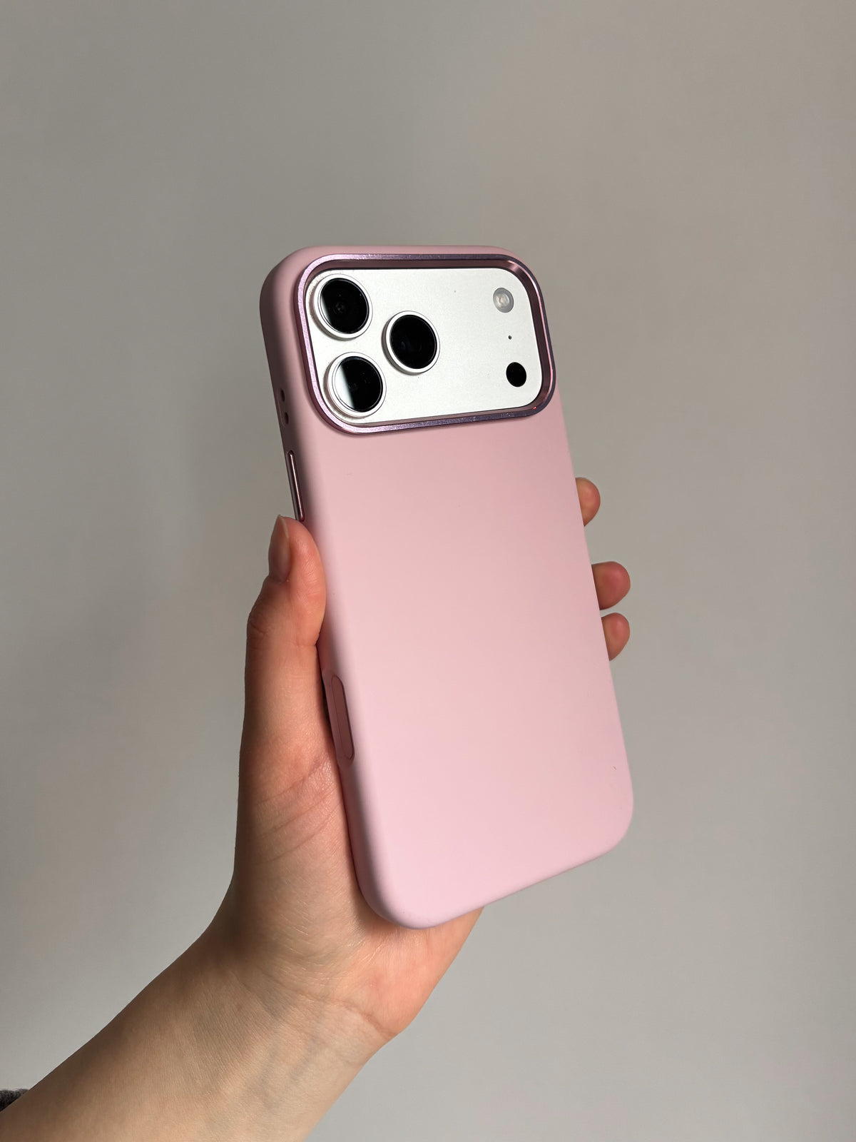 Рожевий чохол на iPhone у руці, вертикально на світлому тлі