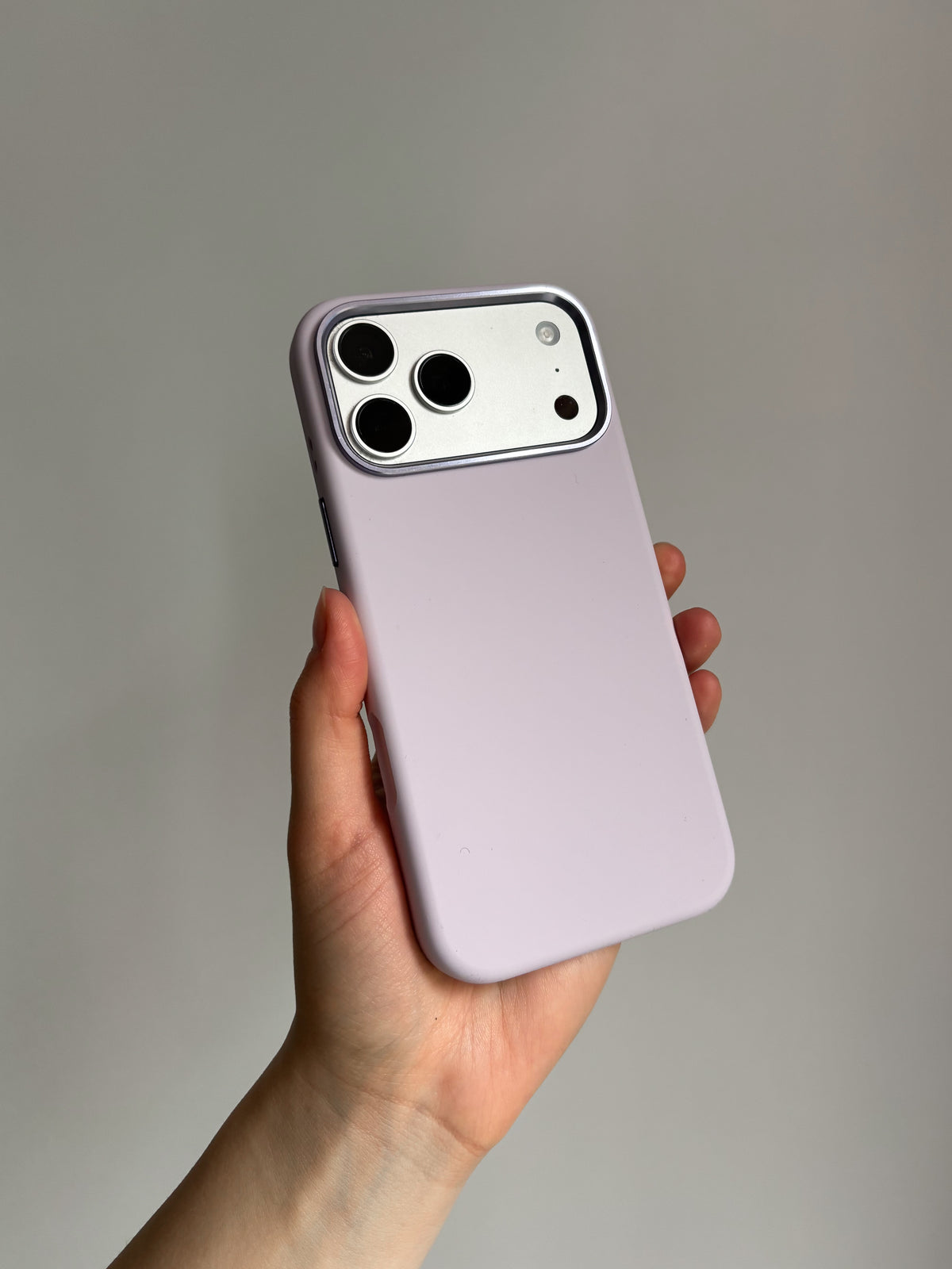 Лавандово-рожевий чохол «Металеві деталі» на iPhone у руці на сірому тлі