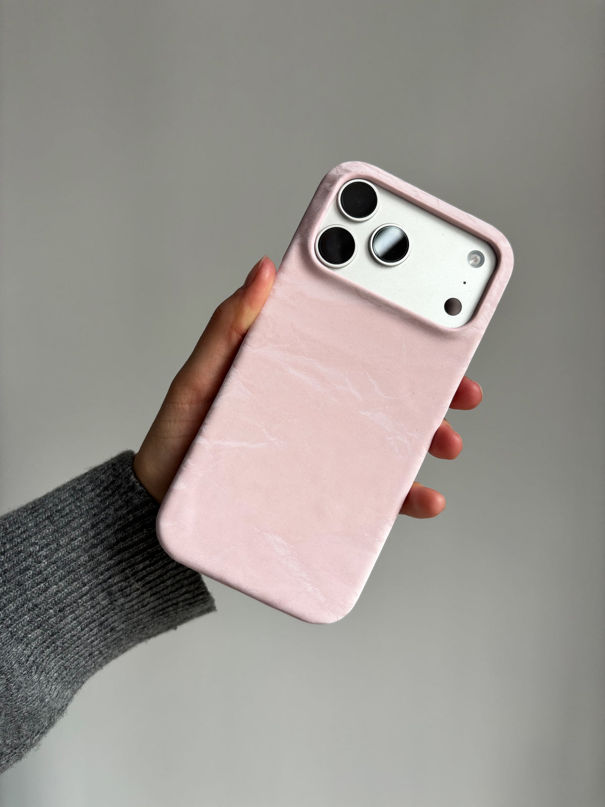 Рожевий чохол «Оксамит» на iPhone у руці в сірому рукаві