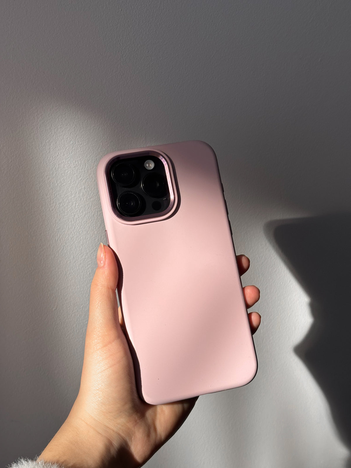 Рожевий чохол «Металеві деталі» на iPhone у руці у грі світла й тіні