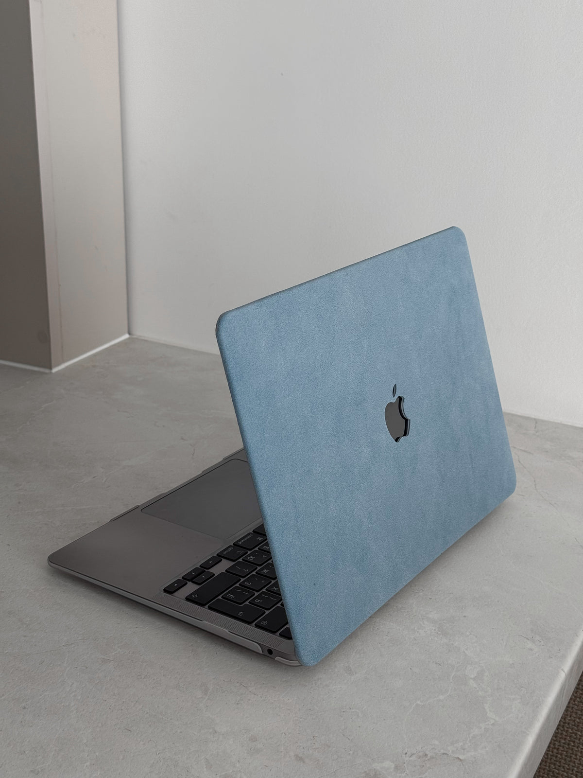 Блакитний чохол «Замшева м’якість» на напіввідкритому MacBook на сірій стільниці