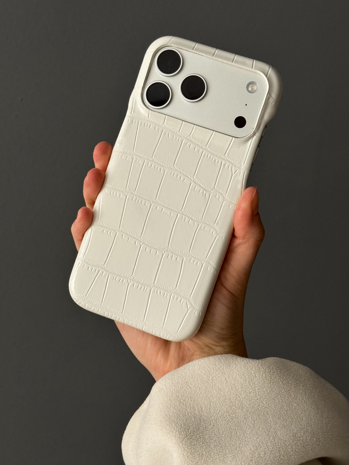 Білий чохол Gator Skin на iPhone у руці на темному тлі