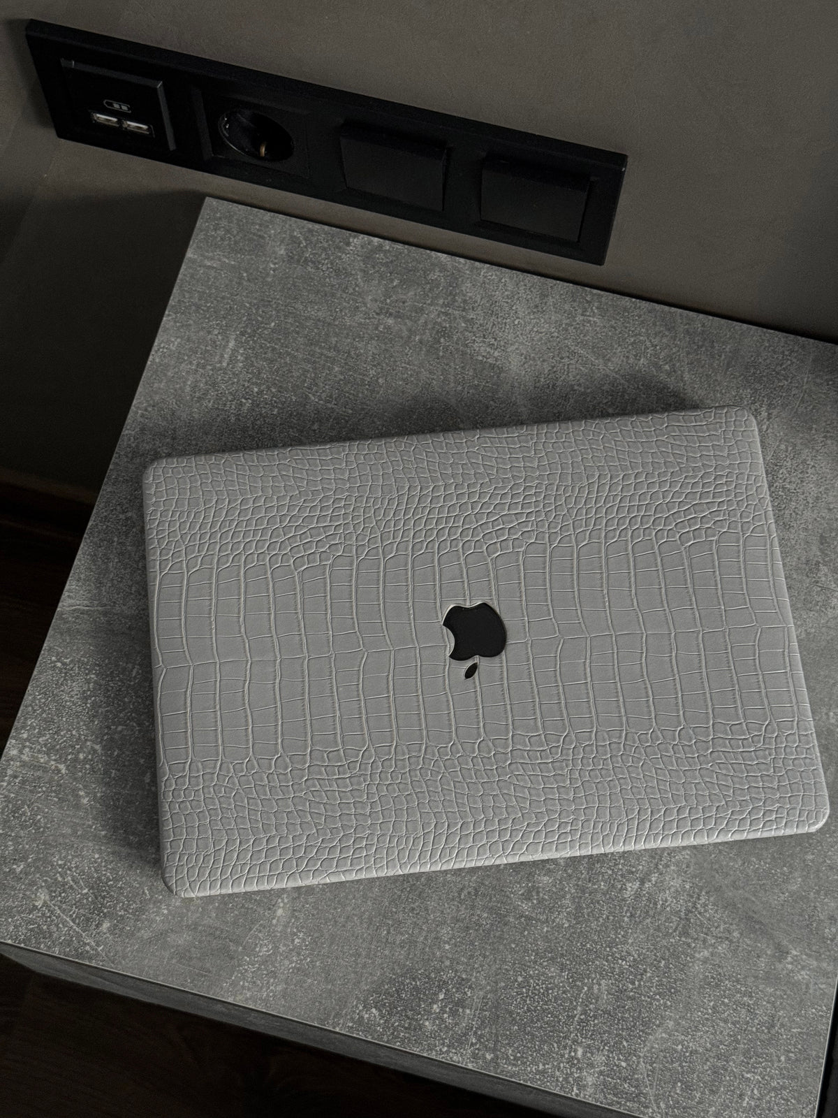 Сірий чохол Gator Skin для MacBook на сірій тумбі