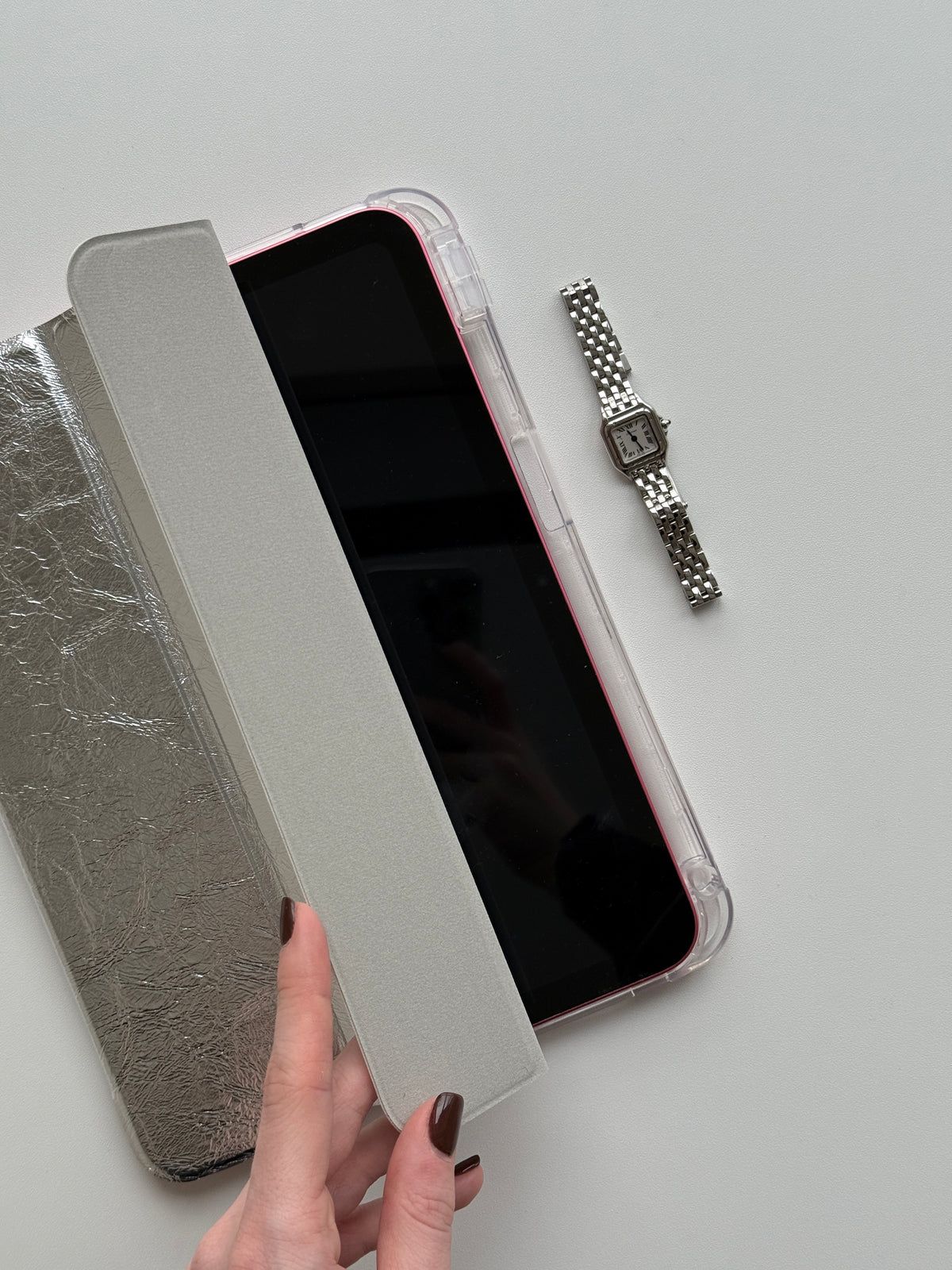 Рука відкриває сріблястий чохол «Текстурне сяйво» — видно iPad у прозорій задній панелі