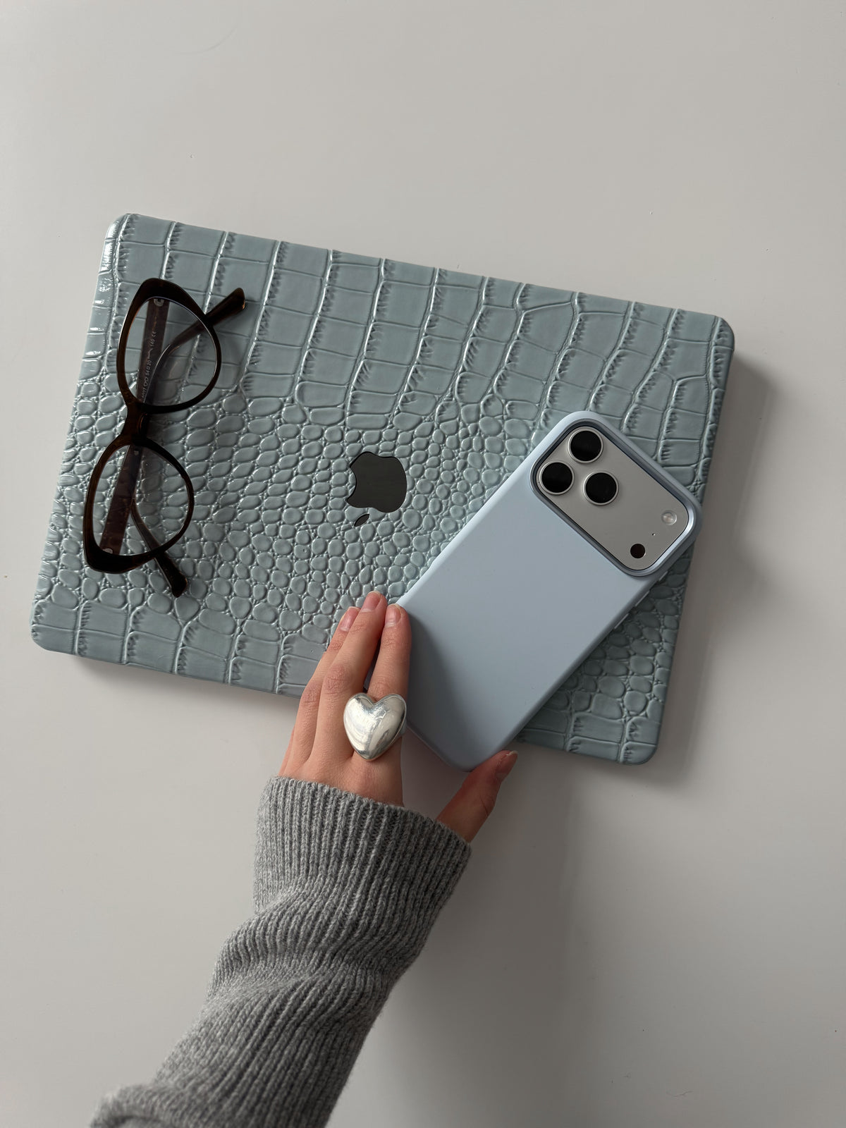 Блакитний чохол Gator Skin для MacBook поруч з окулярами та iPhone у блакитному чохлі