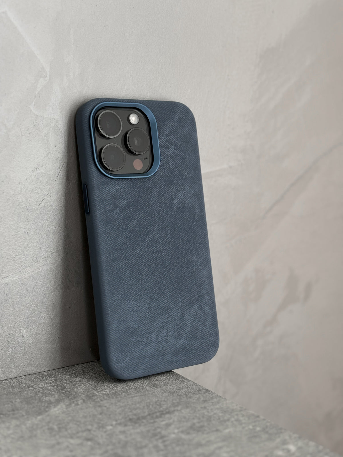 Синій чохол «Замшева м’якість» на iPhone стоїть біля світлої стіни