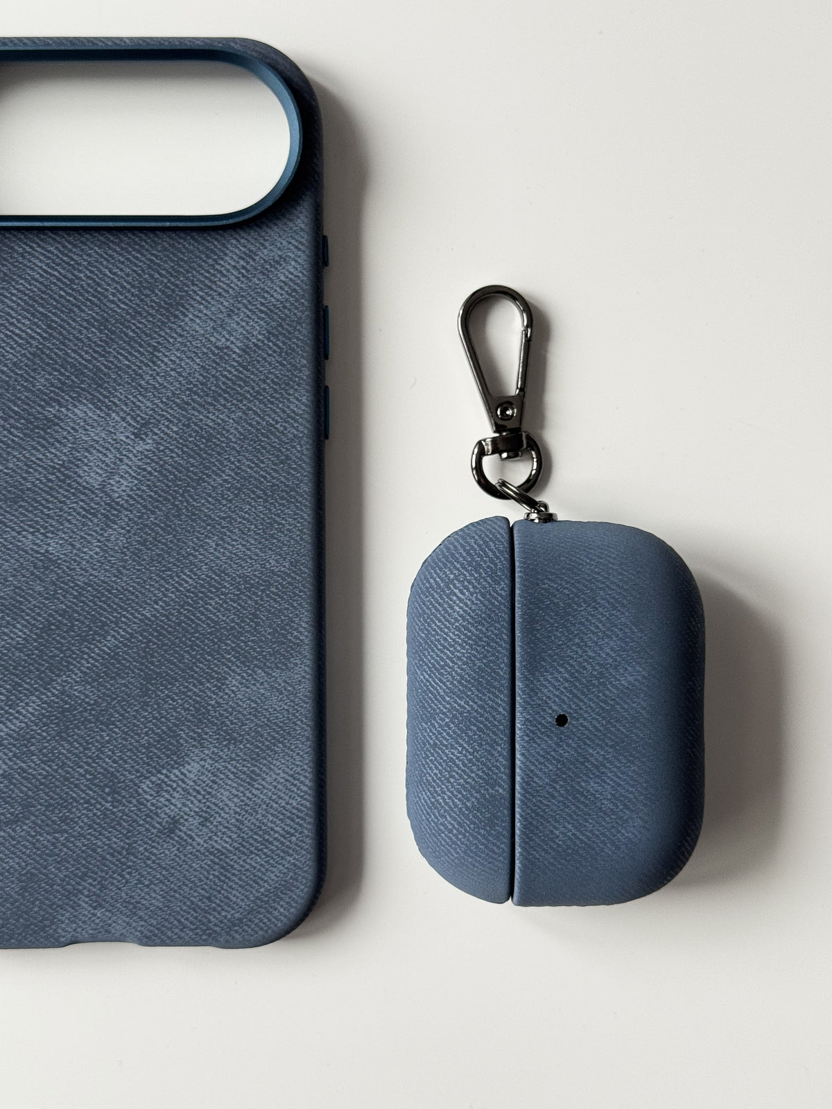 Синій чохол «Замшева м’якість» для AirPods поруч із синім чохлом для iPhone із такою ж фактурою
