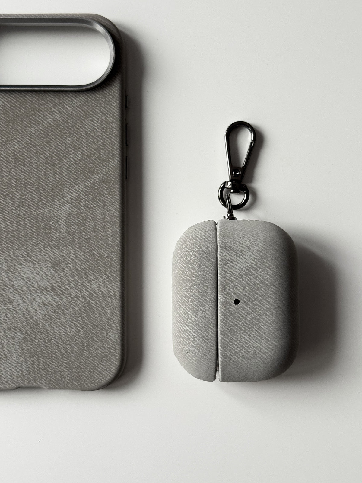 Сірий чохол «Замшева м’якість» для AirPods поруч із сірим чохлом для iPhone із такою ж фактурою