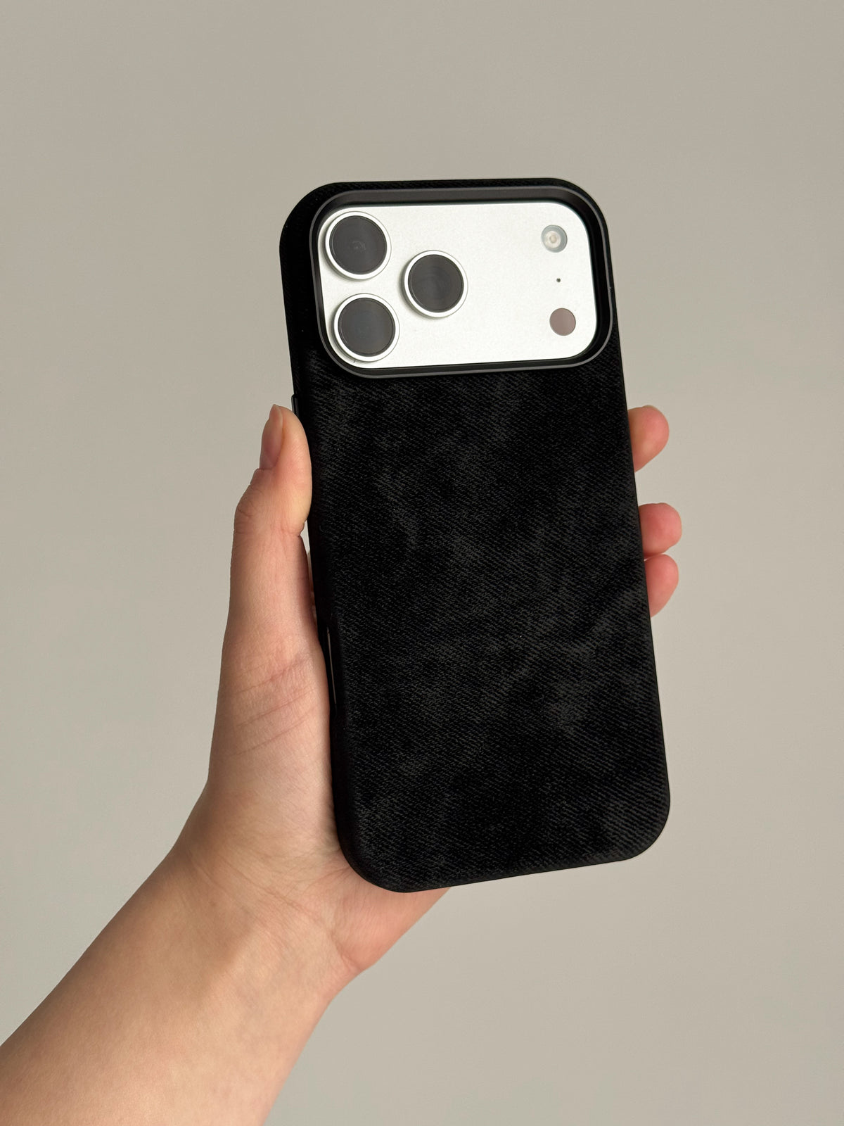 Чорний чохол на iPhone зі світлим блоком камер у руці