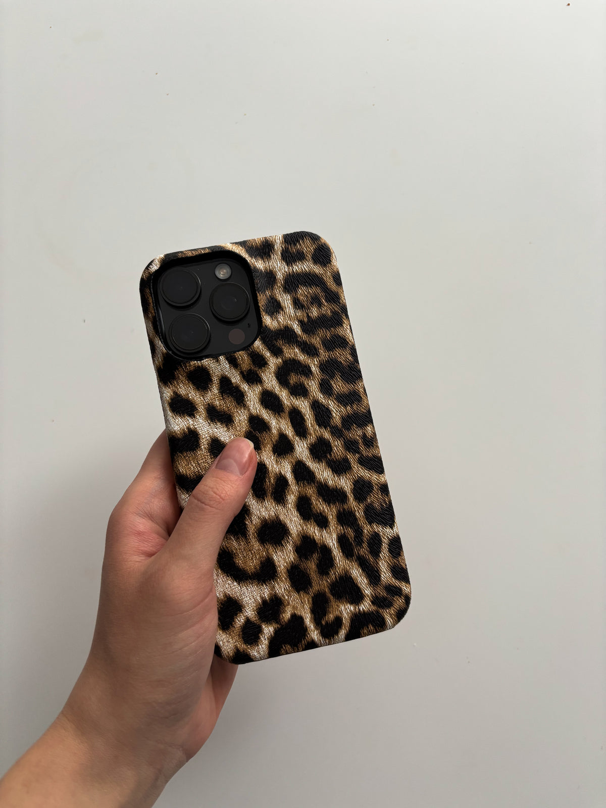 Пісочний леопардовий чохол Leopard на iPhone у руці на світлому тлі