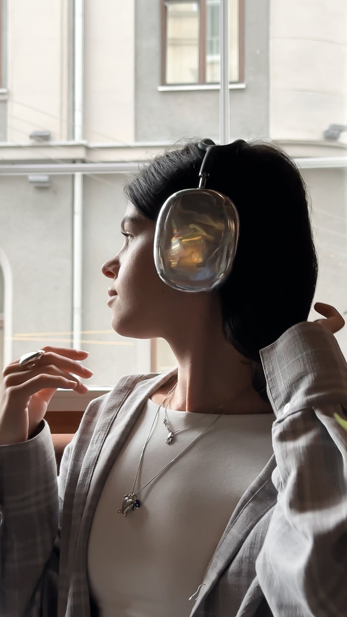 Жінка в навушниках AirPods Max у сріблястих накладках біля вікна