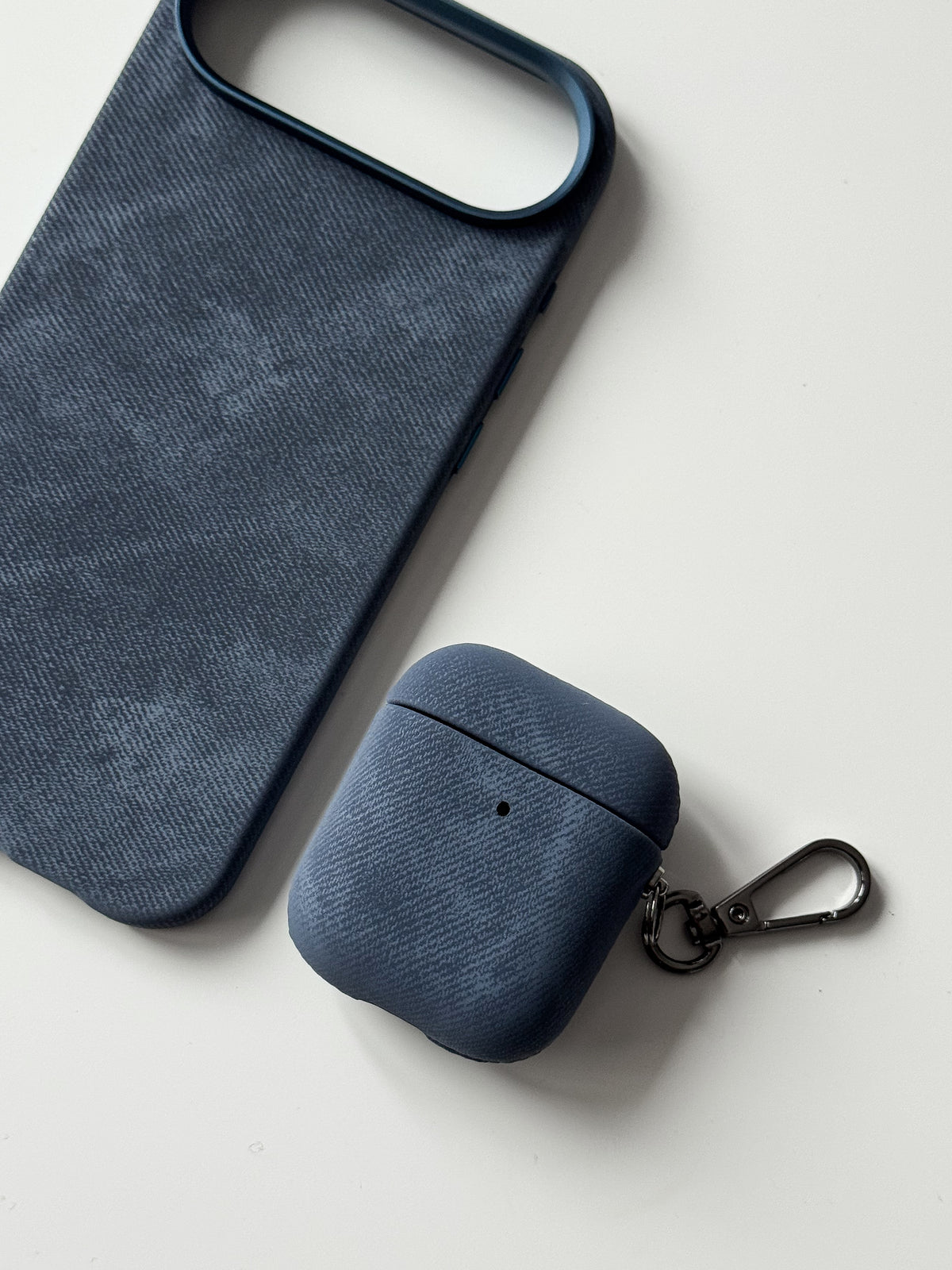Синій чохол «Замшева м’якість» на вужчому кейсі AirPods поруч із чохлом для iPhone