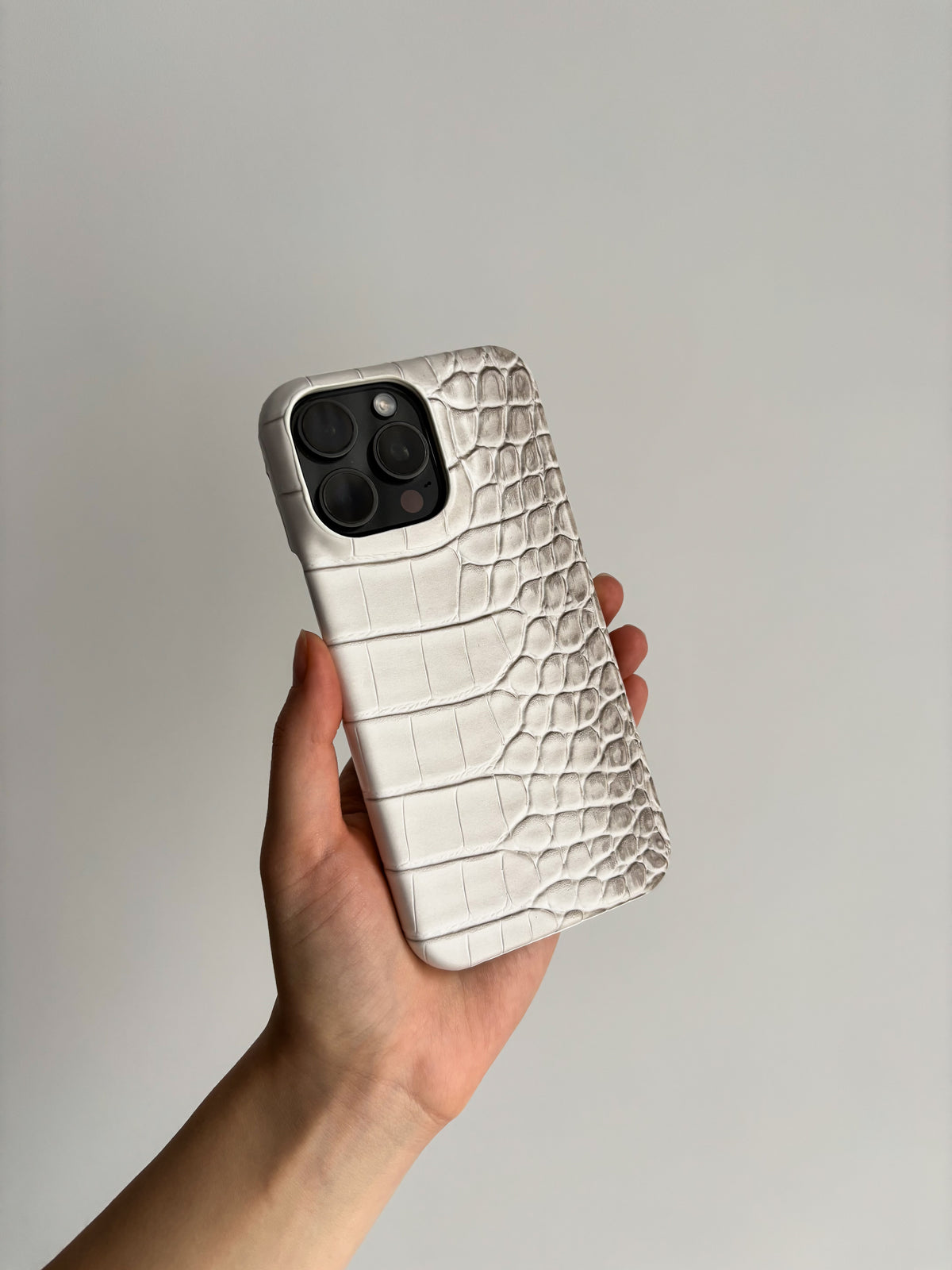 Біло-сірий чохол Gator Skin на iPhone у руці на світлому тлі