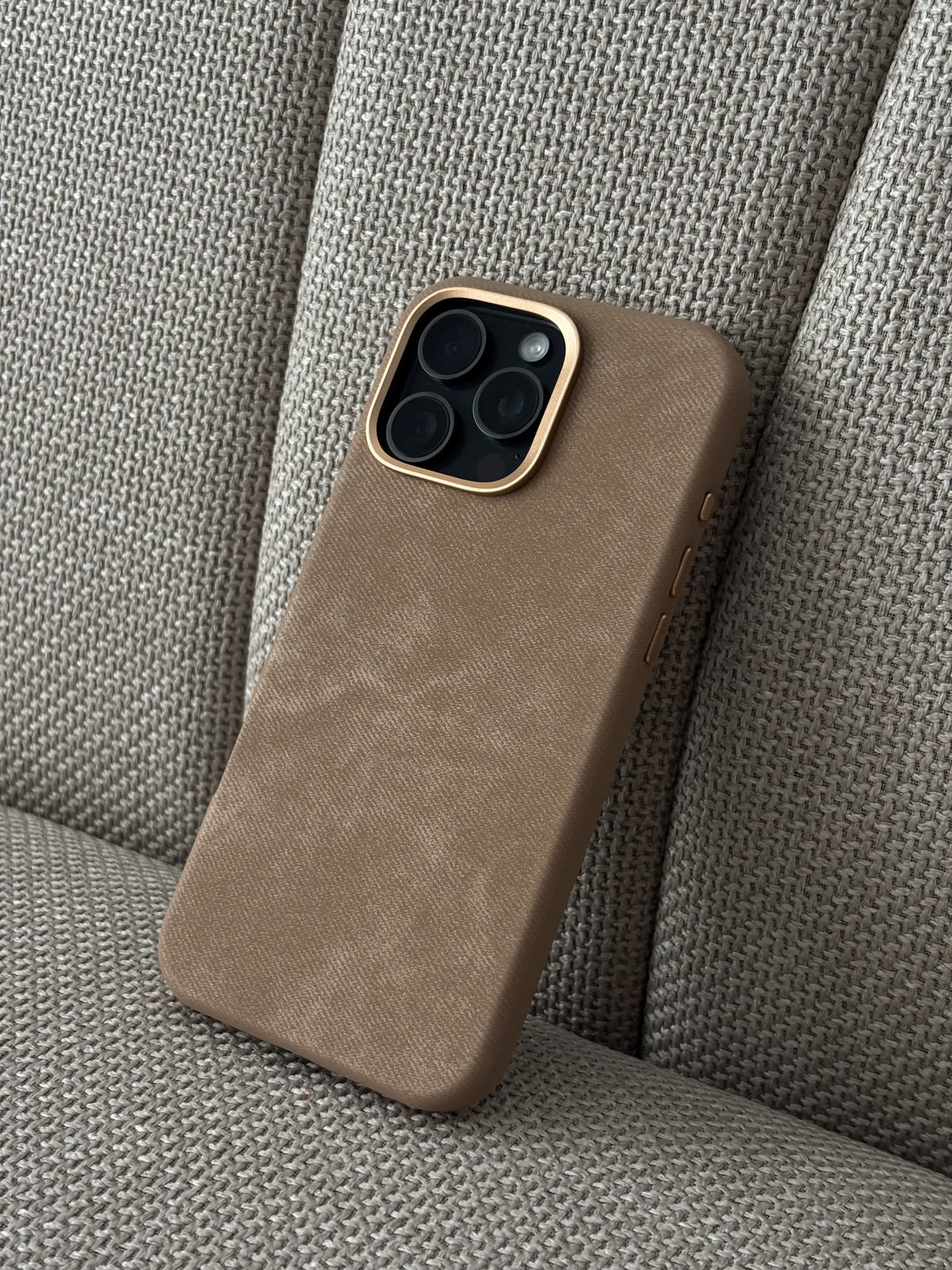 Карамельний чохол для iPhone на сірому текстильному кріслі