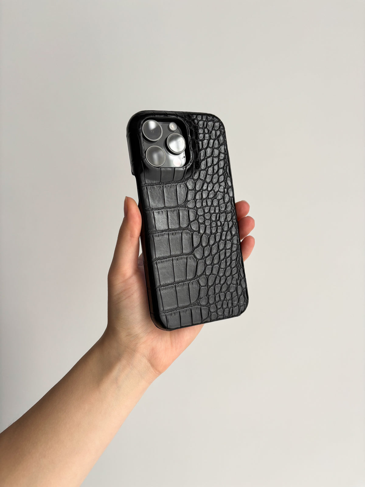 Чорний чохол Gator Skin на iPhone у руці на світлому тлі