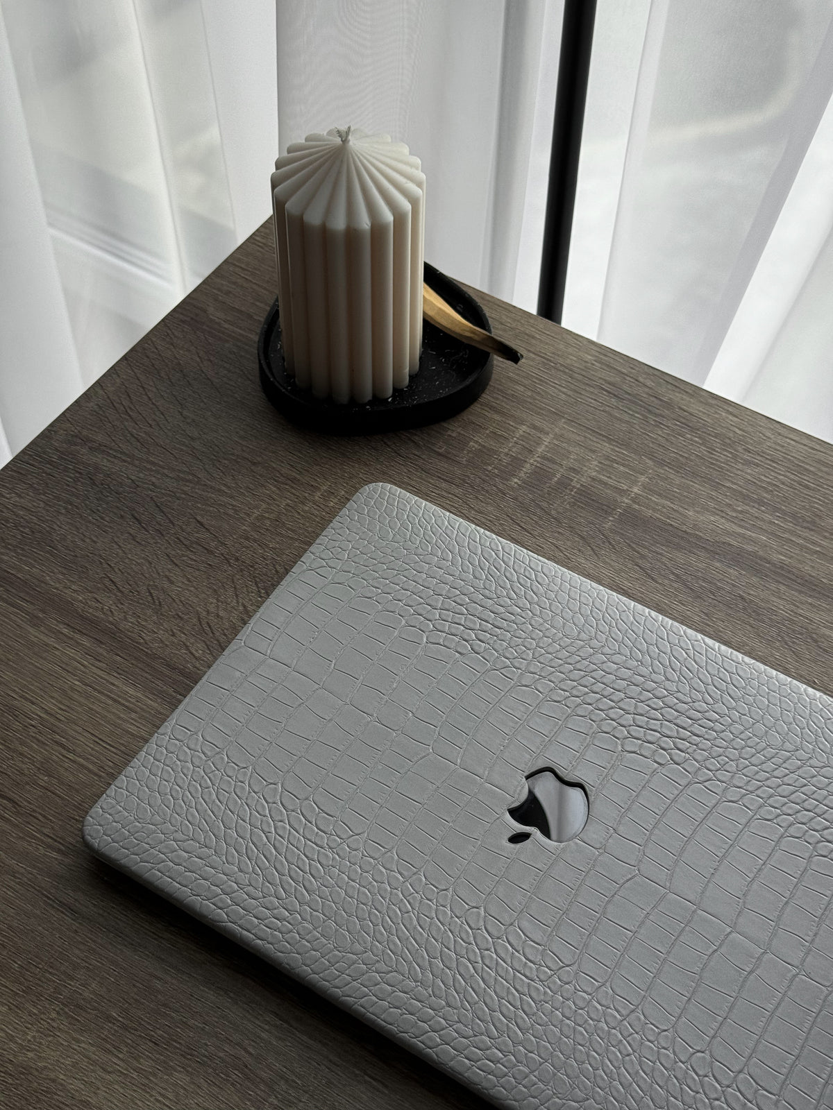 Сірий чохол Gator Skin для MacBook на дерев’яному столі поруч зі свічкою