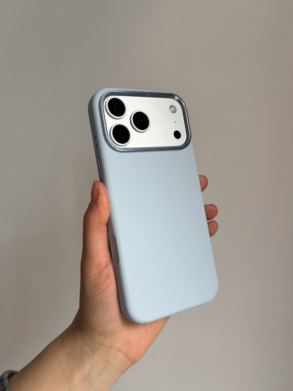 Світло-блакитний чохол «Металеві деталі» на iPhone у руці на сірому тлі